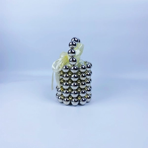 Detail of beaded spherical handbag with silver metal spheres and a yellow satin bow