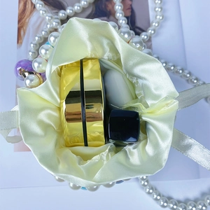 Detail of yellow satin drawstring pouch with pearl strap and internal makeup storage