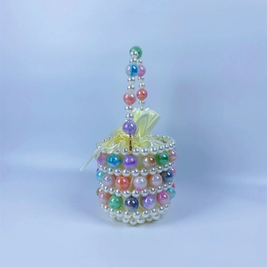 Macro shot of colorful beads on a white pearl bucket bag with a yellow satin drawstring liner