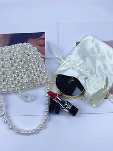 Handmade woven pearl bucket handbag with satin drawstring pouch on white background