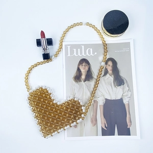 Detailed top view of handmade heart-shaped beaded bag with amber beads and pearls