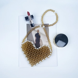 Detail of amber heart beaded crossbody bag with pearl trim and stylish lifestyle props