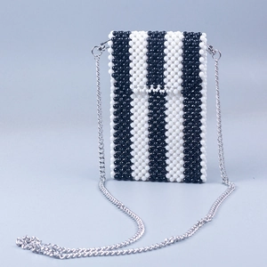 Detail of handmade beaded mini bag with black and white stripes and silver metal chain