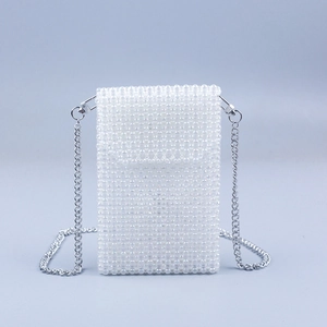 Macro shot of white pearl beaded mini crossbody bag with delicate silver chain strap