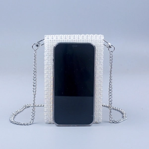Detail of white beaded phone bag with silver chain strap showing phone size fit