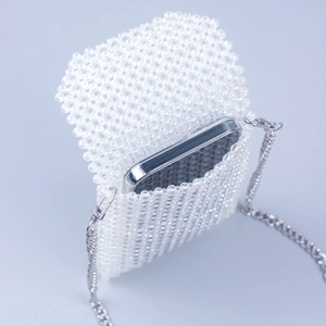 Detail of handmade beaded phone bag with white round beads and silver metal chain strap