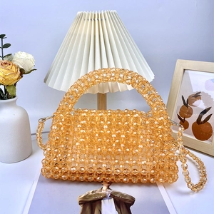Detalle del tejido de cuentas naranja ámbar y textura acrílica brillante del bolso
