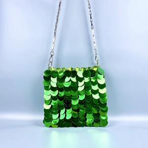 Close-up of green sequin handbag featuring a metallic fish scale texture and silver chain