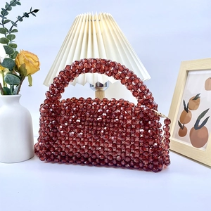 Detalle de bolso de mano rojo oscuro con cuentas de acrílico tejidas y asa resistente