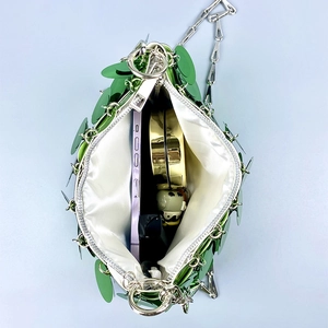 Detail view of green sequin bag interior with smartphone and makeup accessories