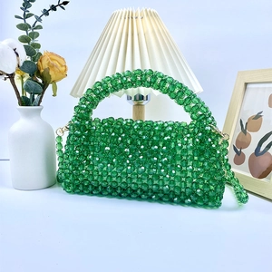 Detalle del bolso de cuentas acrílicas tejido a mano verde esmeralda con herrajes de metal dorado