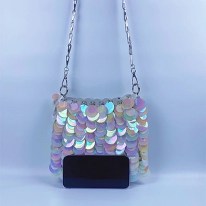 Macro shot of shimmering fish-scale sequins and silver chain on a mini crossbody bag