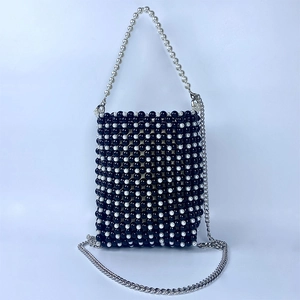 Close-up of woven black and white beaded handbag with silver chain strap and top handle