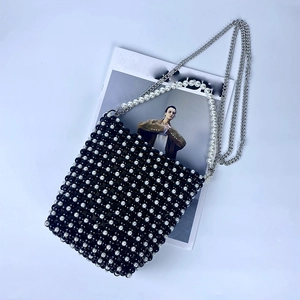 Close-up of black and white beaded bag with pearl handle and metal chain strap