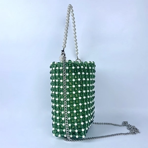 Detail of green beaded mini bucket bag with white pearl handle and metal chain strap