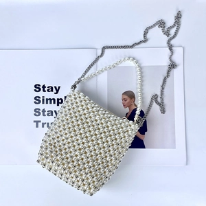Detail view of woven pearl crossbody bag with silver chain and white bead texture