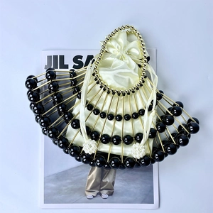Detail of a fan-shaped shell bag with golden metal frame, black beads and satin inner pouch
