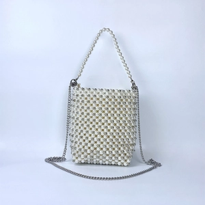 Detailed view of white woven pearl handbag with silver chain strap and pearl handle