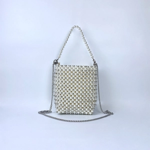 Close-up of a white pearl woven mini bag with a silver chain strap and beaded handle