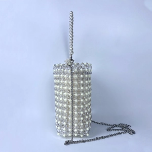 Detail of handmade beaded bucket bag featuring pearl handle and silver chain strap