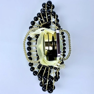 Detail of woven shell handbag with black beads and gold frame holding cosmetics