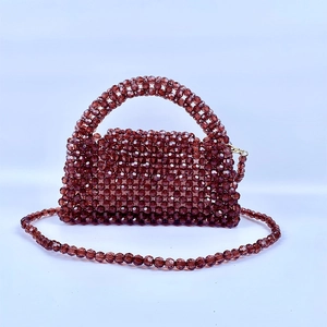 Detalle de bolso tipo almohada de cuentas marrón café con asa y correa de acrílico