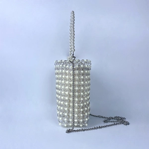 Close-up of elegant pearl-beaded mini bag featuring a silver chain and woven handle