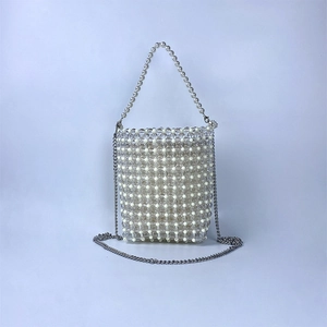 Detailed view of woven bead bag featuring clear pearls and silver metal chain strap