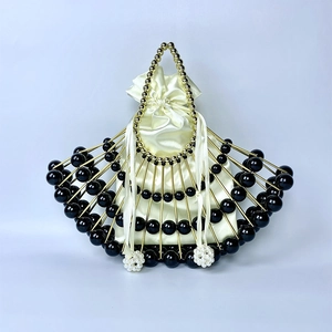Macro view of shell bag showing golden metal frame with black beads and pearl details