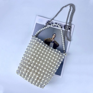 Detailed close-up of handmade woven pearl handbag with silver chain and bead handle