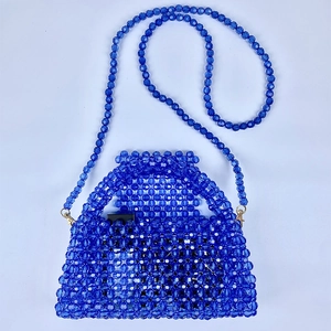 Detalle del bolso de cuentas azules con tejido acrílico y cadena metálica dorada de lujo