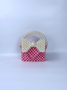 Detail van roze kralen handtas met grote witte strik en handgeweven parelstructuur