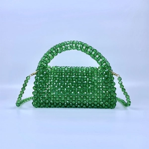 Detalle del bolso de cuentas verde esmeralda hecho a mano con textura tejida y cierres oro