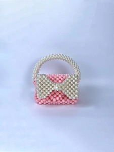 Detail van roze kralen handtas met witte parelmoer strik en decoratief handvat