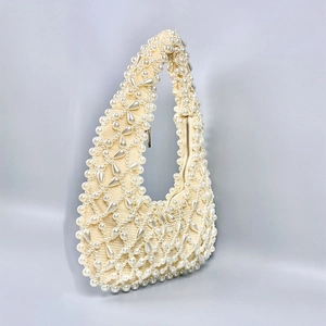Detailed view of intricate pearl embroidery and beadwork on a crescent hobo handbag