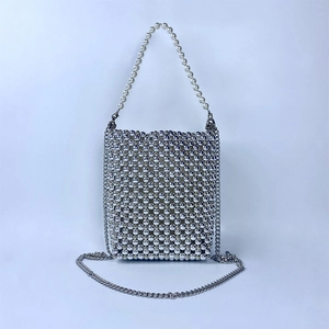 Macro detail of silver beaded handbag with large pearl handle and metal chain strap