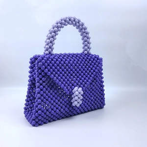 Dettaglio macro della borsa a trapezio fatta a mano con perline viola intrecciate