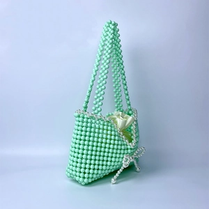 Detailed macro of mint green beaded handbag with pearl bow and satin lining