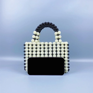 Detail view of the beaded handbag next to a smartphone for size reference and scale
