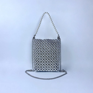 Macro shot of silver beaded mini handbag featuring white pearl handle and metal chain
