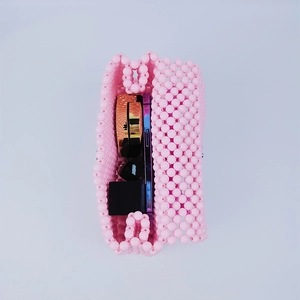 Vista dell'interno della borsa di perline rosa con telefono, trucco e oggetti quotidiani