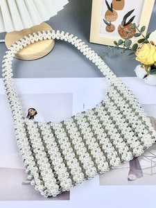 Sac hobo fait main en perles avec détails argentés posé sur un magazine de mode