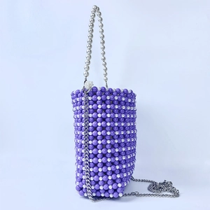 Detail of purple and white beaded bucket bag with pearl handle and metal chain