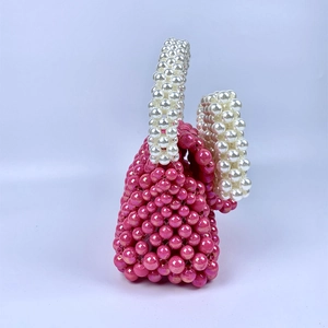 Detail van roze kralen handtas met witte parel handvatten en handgemaakt weefwerk