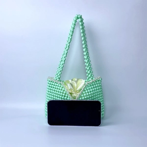 Detail of mint green beaded handbag with white pearl trim and yellow satin pouch liner