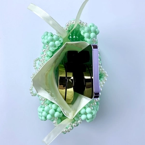Detail view of mini green beaded bag with white satin lining showing interior storage space