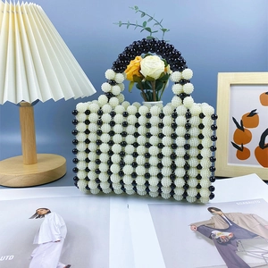 Detail of hand-woven black and white beaded handbag with retro resin round top handle