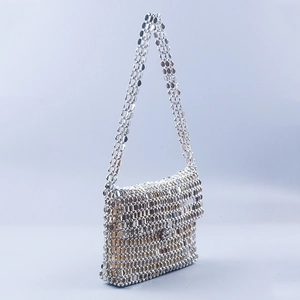 Detail of silver metallic disc sequins and handcrafted chainmail texture on a shoulder bag