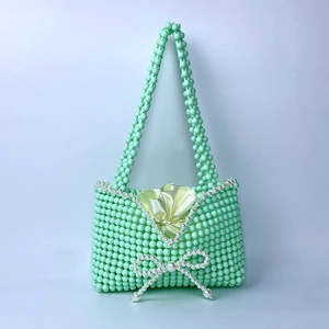 Detail view of handmade mint green beaded handbag with pearl bow and satin lining