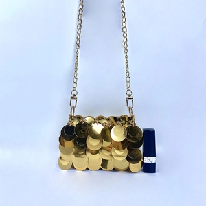 Macro shot of gold sequin mini bag with chain strap and lipstick for size reference